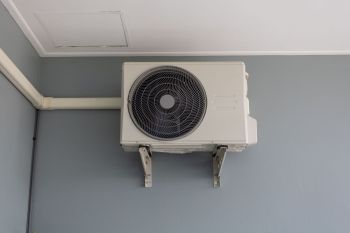 Outdoor heat pump unit mounted beside a home.