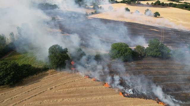 Aerial view of a field with active flames and smoke.