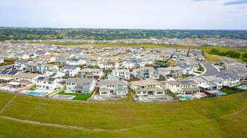 Aerial view of a suburban neighborhood with various houses and green areas on a hillside.