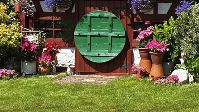 A "Hobbit House" with a round door flanked by potted flowers.
