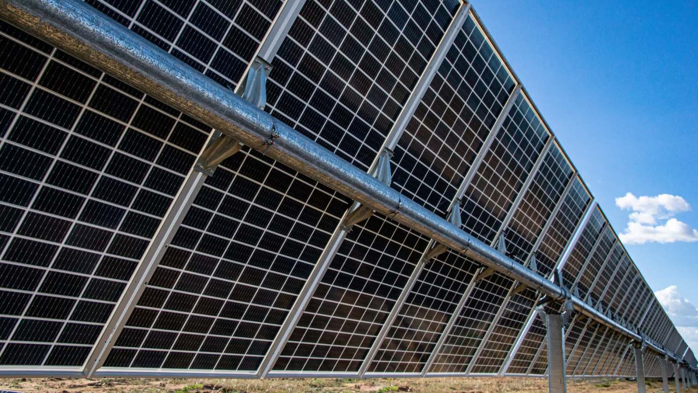 A close-up view of bifacial solar panels angled toward a clear blue sky.