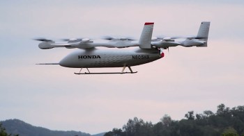 A Honda electric aircraft flying on a cloudy day.