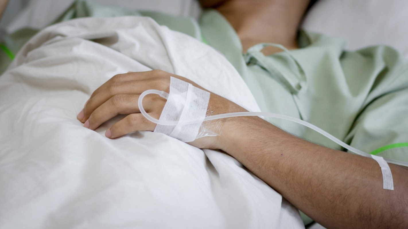 A person with an IV in a hospital bed.