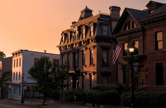 A historic brick building with an American flag at sunset.