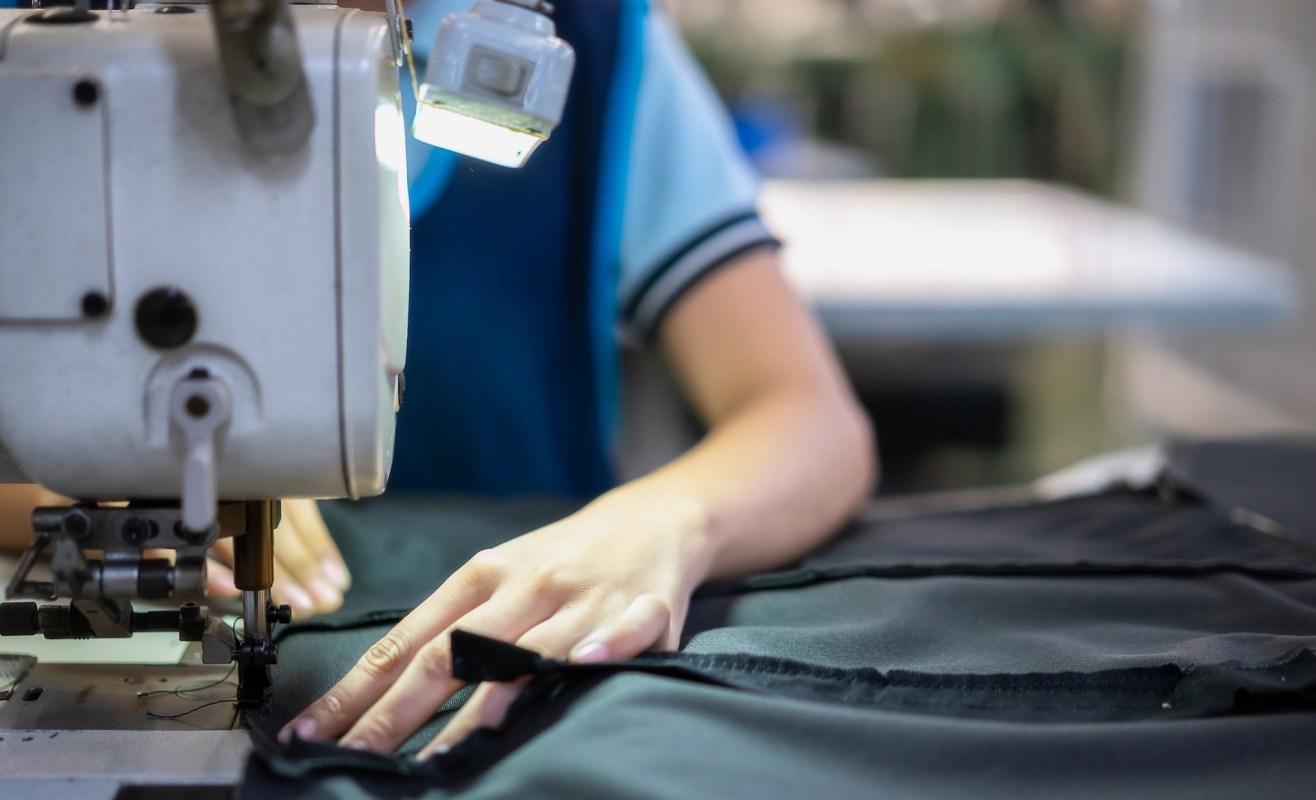 A person using a sewing machine in a workshop setting.