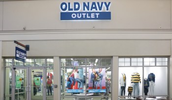 An Old Navy Outlet store front displaying promotional posters and mannequins dressed in casual clothing.
