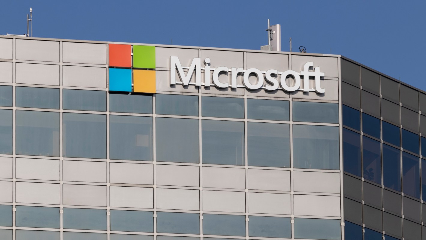 A close-up view of the Microsoft logo on a modern building against a clear blue sky.