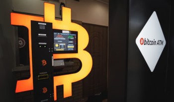 A Bitcoin ATM with a bright logo and user interface displaying buy and sell options.