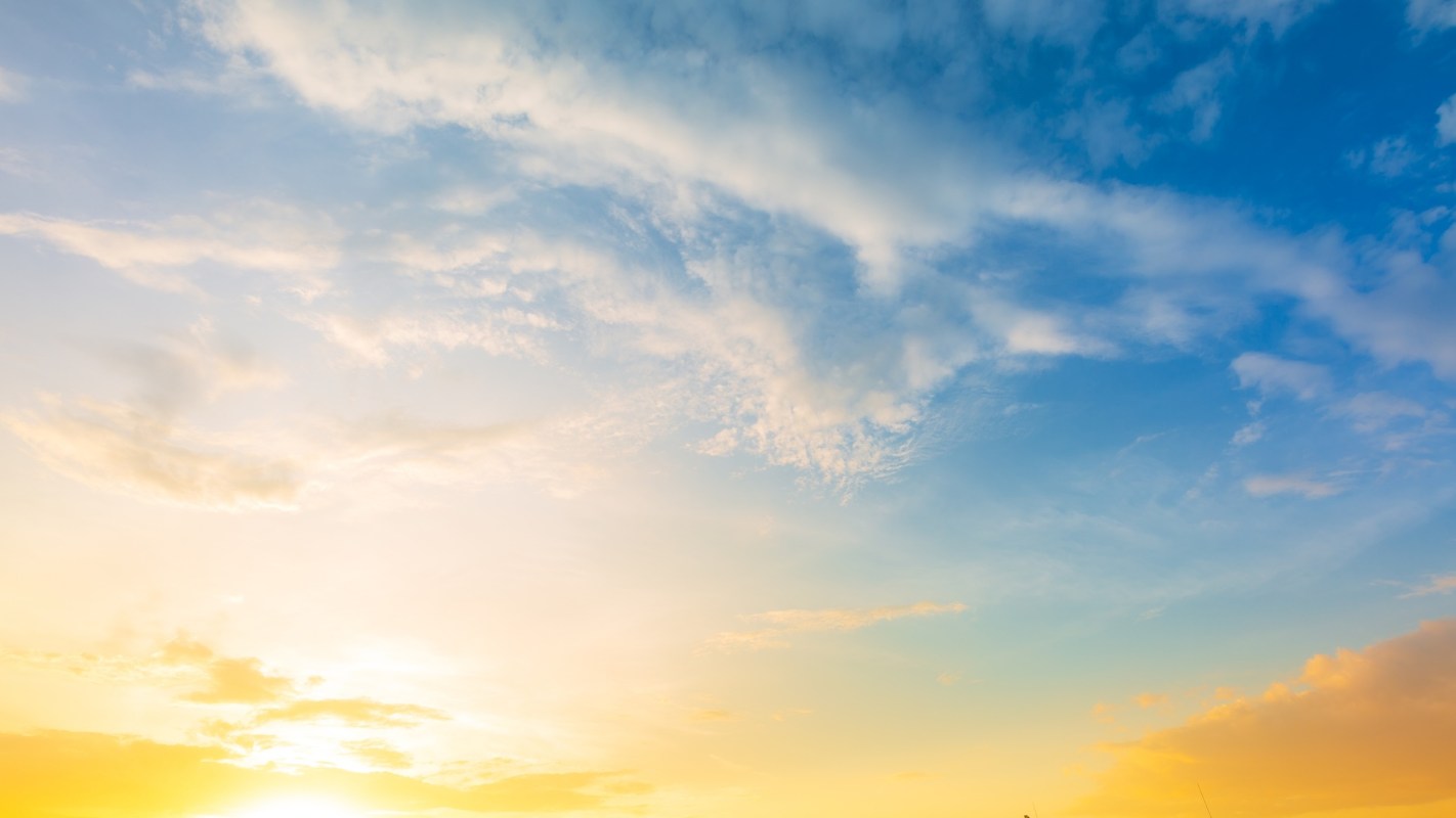 A vibrant sky with soft clouds transitioning from warm yellow to blue.