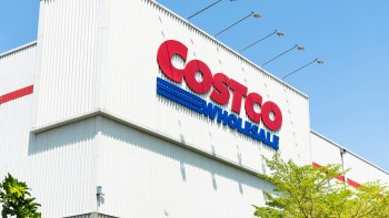 A close-up of the Costco Wholesale store sign against a clear blue sky.