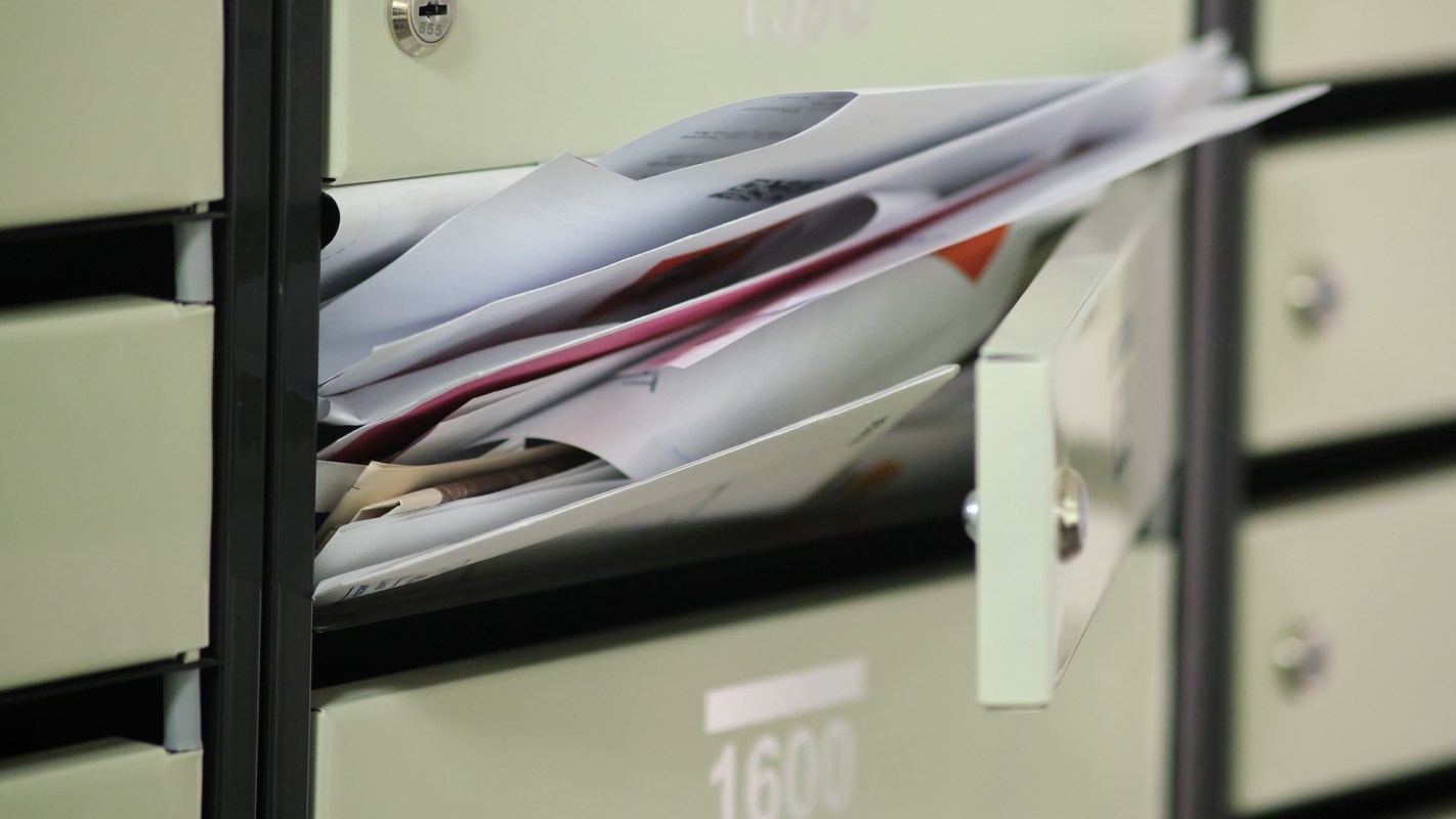 A open mailbox with junk mail spilling out.