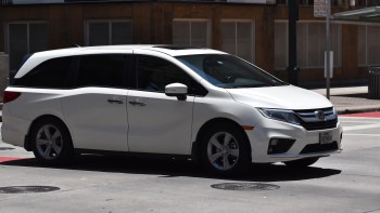 A white Honda Odyssey minivan goes through a city intersection .