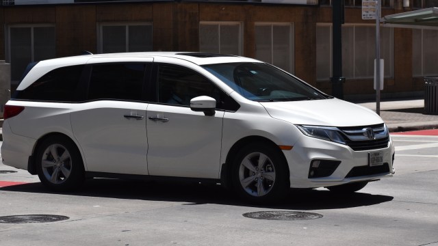 A white Honda Odyssey minivan goes through a city intersection .