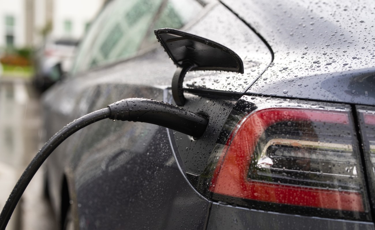 A black Tesla charging port in the rain.