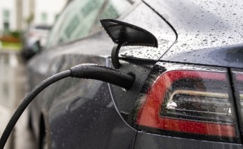 A black Tesla charging port in the rain.