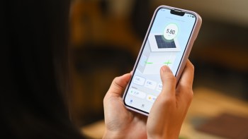 A person holding a smartphone displaying a solar energy monitoring app with usage statistics.