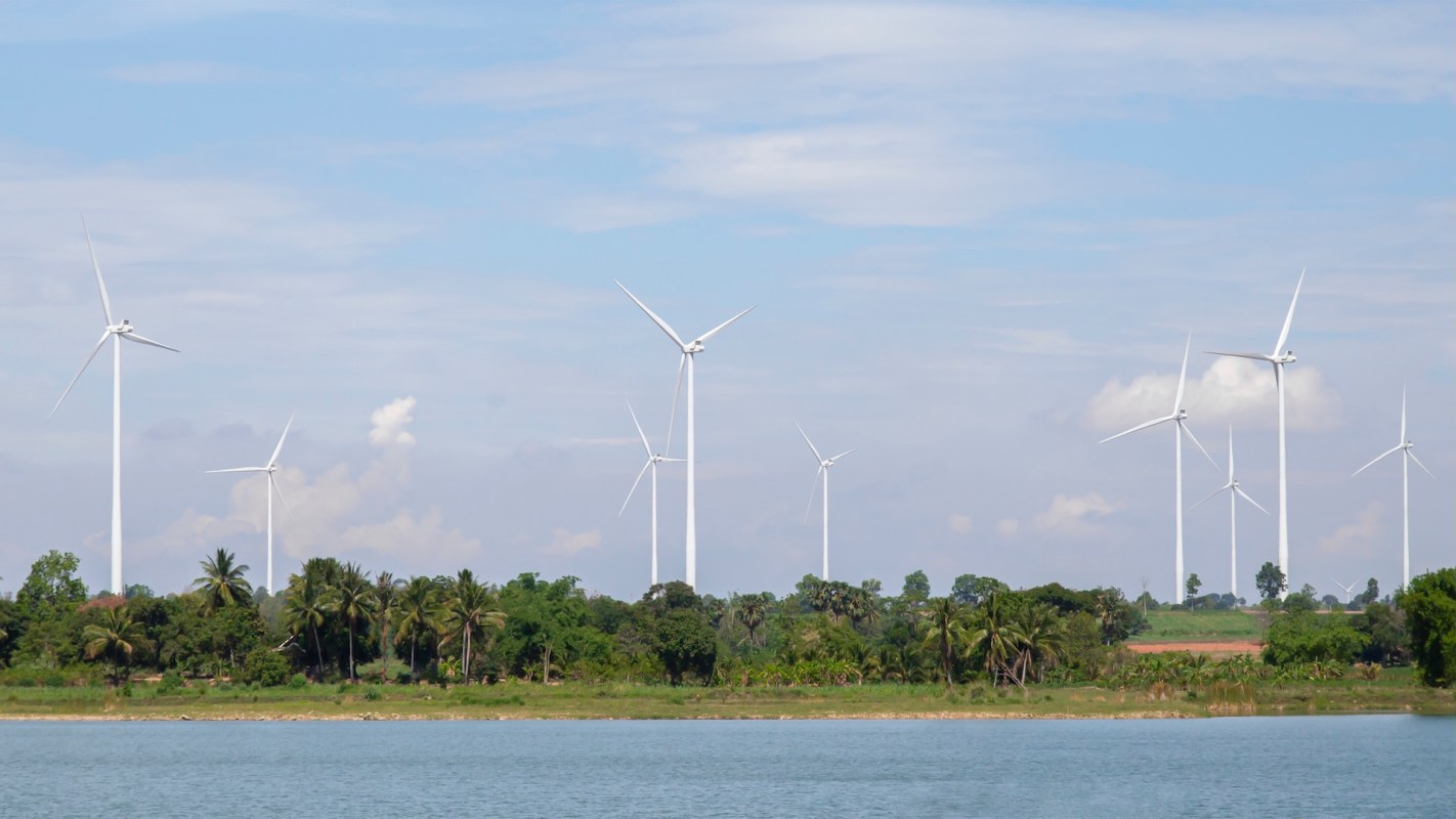 A row of wind turbines near a shoreline.
