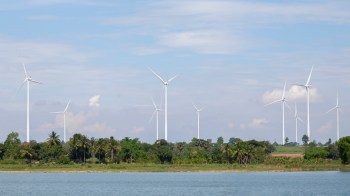A row of wind turbines near a shoreline.