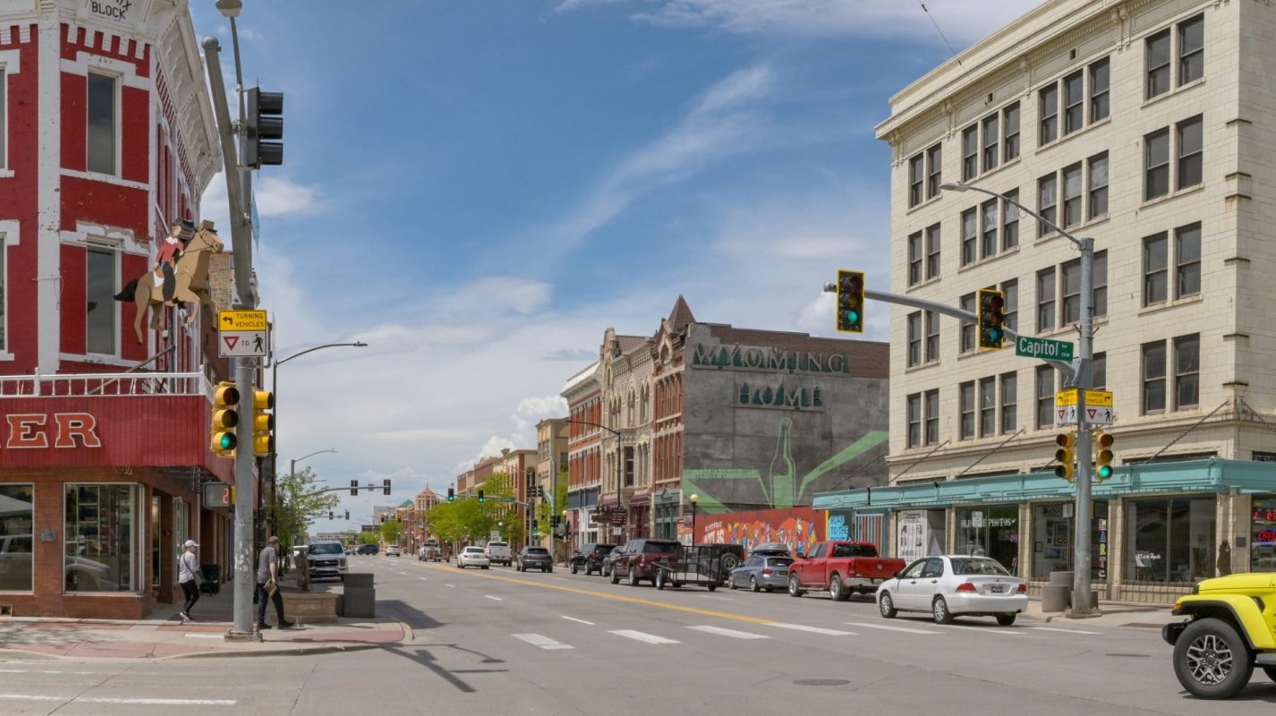 A street scene in Cheyenne, Wyoming, featuring historic buildings, traffic signals, and pedestrians.