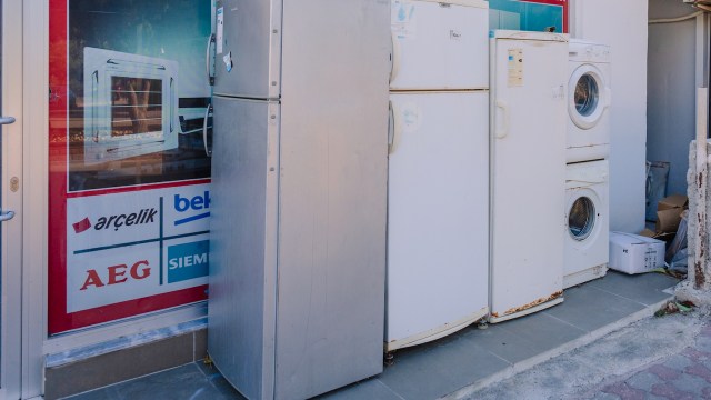 Two refrigerators and a washing machine outside a store front.