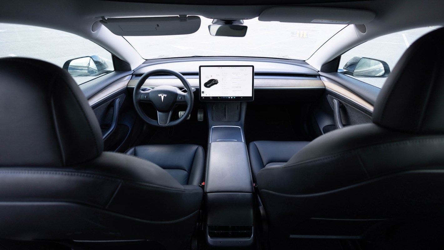 A sleek interior of a Tesla vehicle featuring a large touchscreen display and leather seats.