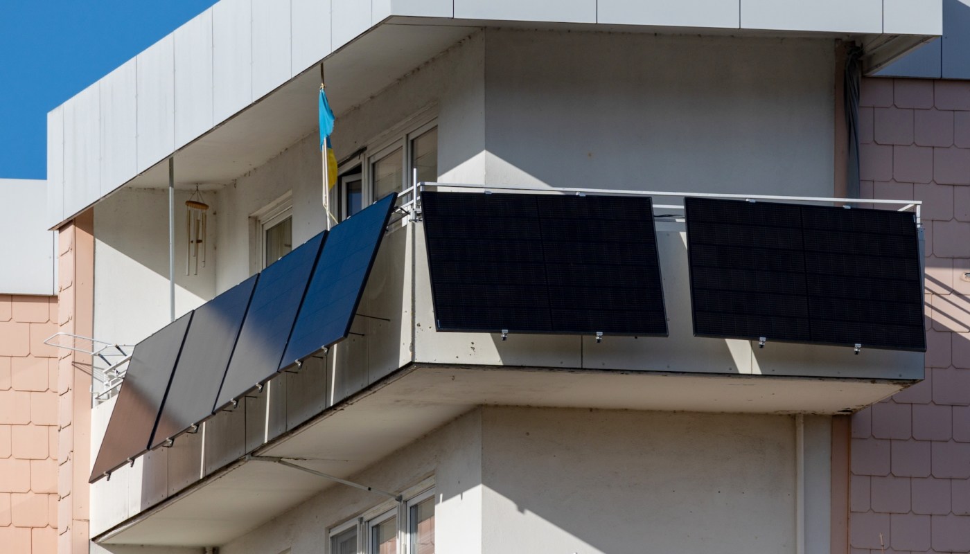 A balcony featuring multiple solar panels against a clear blue sky.