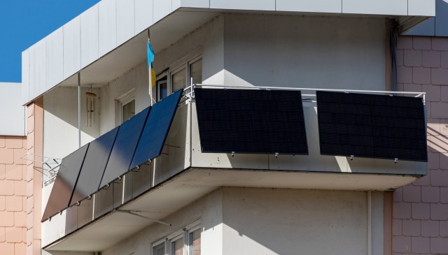 A balcony featuring multiple solar panels against a clear blue sky.