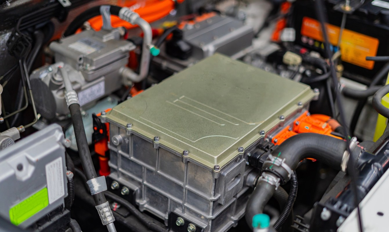 A close-up view of an electric vehicle's engine compartment showcasing the power electronics module and wiring.