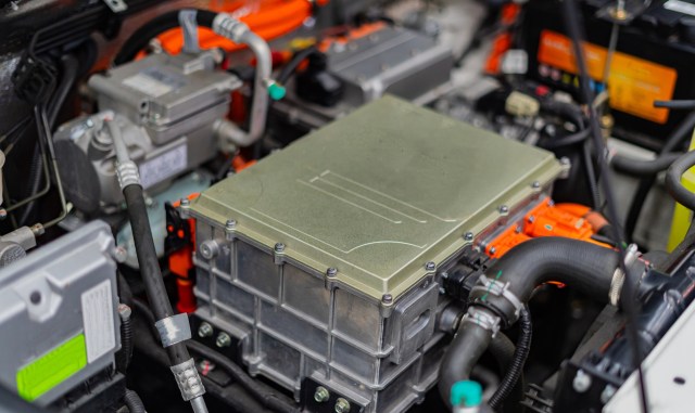 A close-up view of an electric vehicle's engine compartment showcasing the power electronics module and wiring.