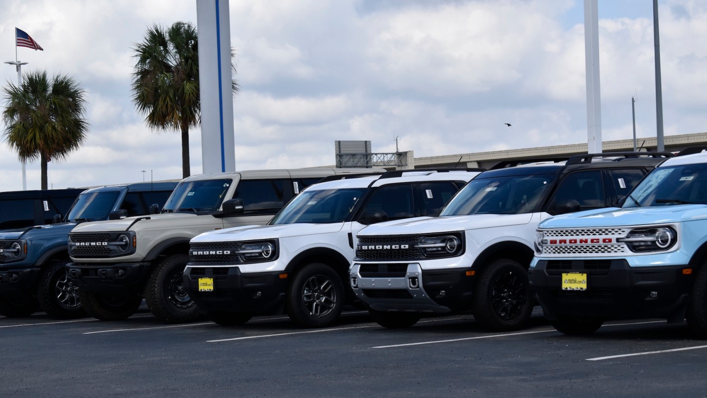 A row of Ford Bronco SUVs in various colors at a dealership.