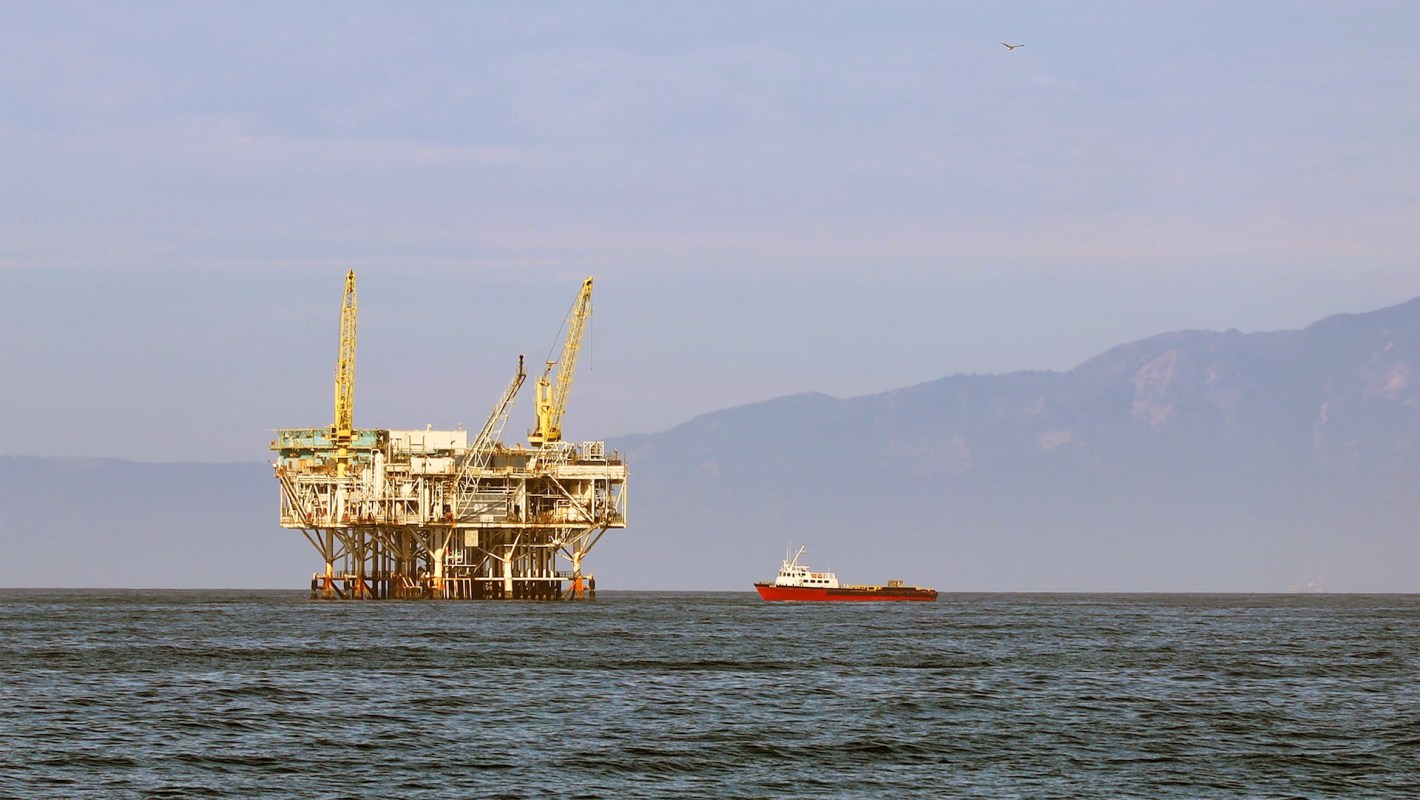 A boat next to an offshore oil platform.