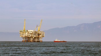 A boat next to an offshore oil platform.