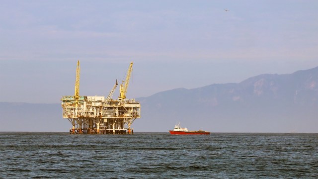 A boat next to an offshore oil platform.