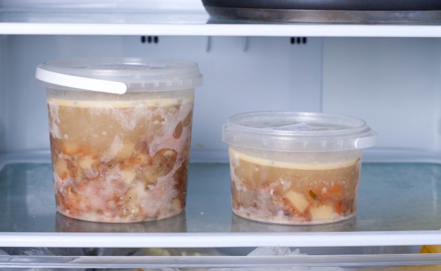 Two containers of frozen soup with visible ingredients, stored in a refrigerator.