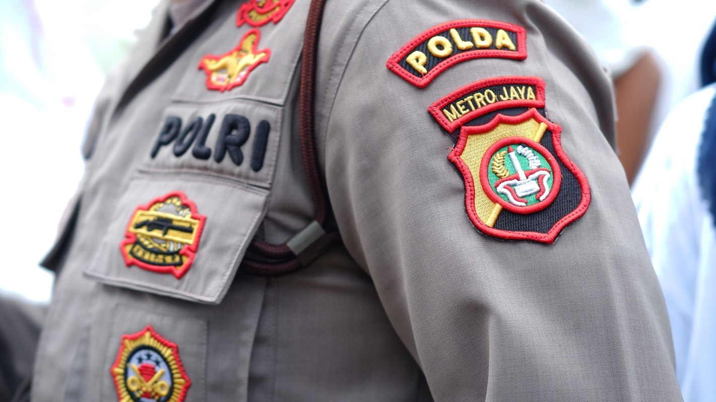 A close-up of a police uniform sleeve featuring various badges and insignia.