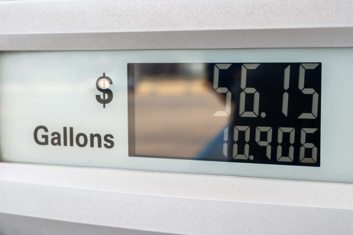 A fuel pump display showing a price of $56.15 and a volume of 10.906 gallons.