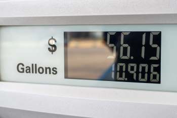 A fuel pump display showing a price of $56.15 and a volume of 10.906 gallons.