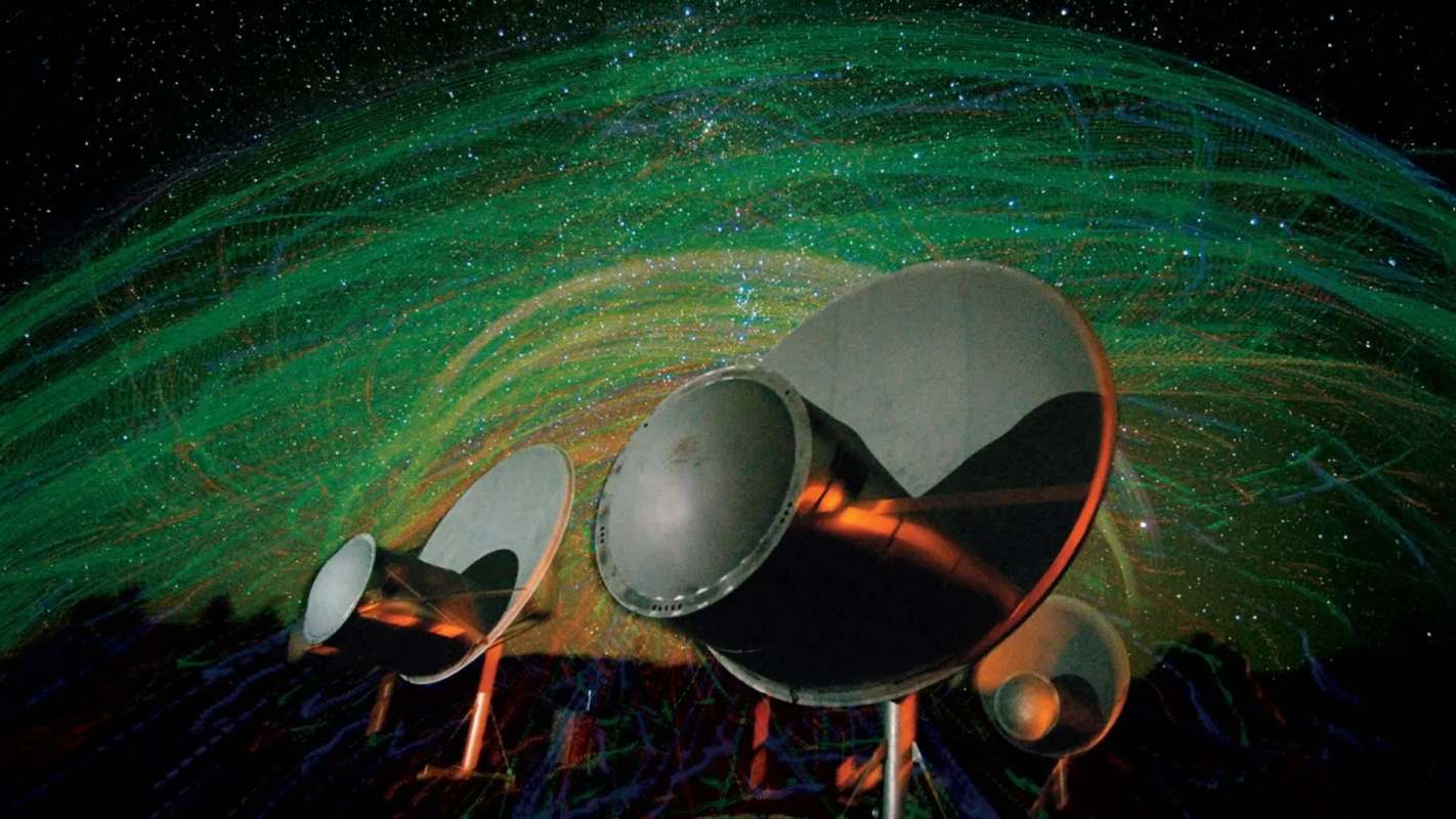 Three large satellite dishes are set against a colorful starry background with swirling green and blue patterns.