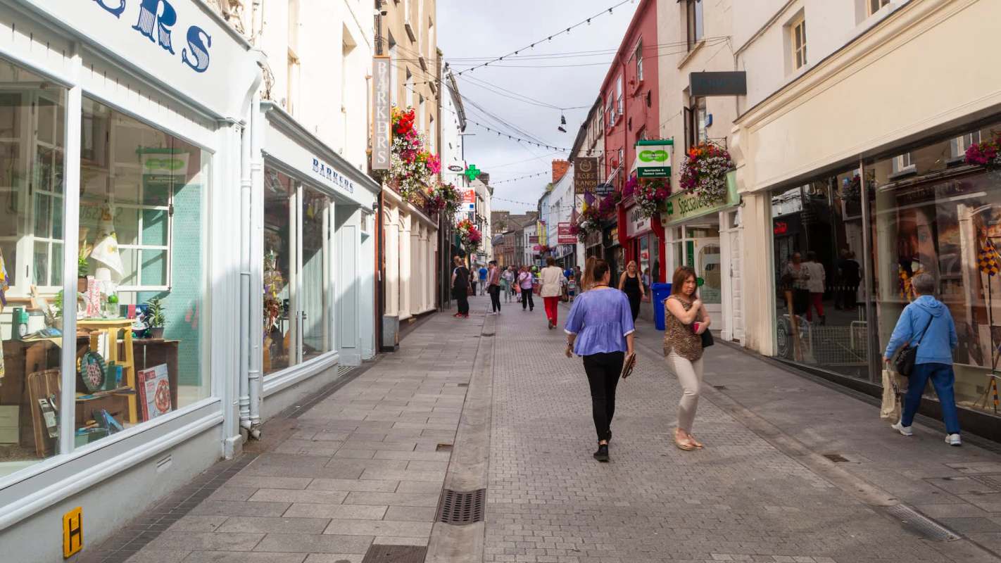 A bustling street lined with colorful shops and pedestrians walking leisurely through a vibrant shopping area.