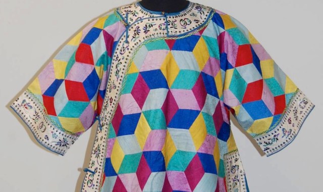 A colorful patterned garment featuring geometric shapes and embroidered detailing along the neckline and sleeves.