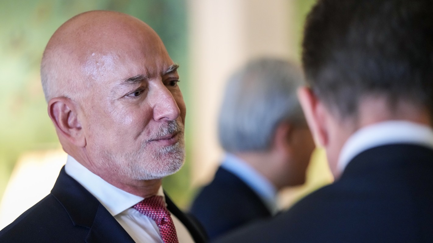 Jeff Bezos engages in conversation, with another person partially visible in the background.