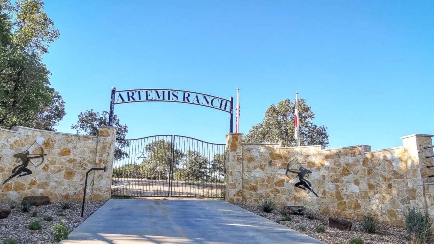A gate and stone wall in front of Artemis Ranch.