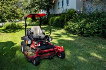 A riding lawn mower at a standstill on a grass lawn.