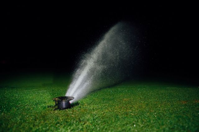 A sprinkler emitting water at night.