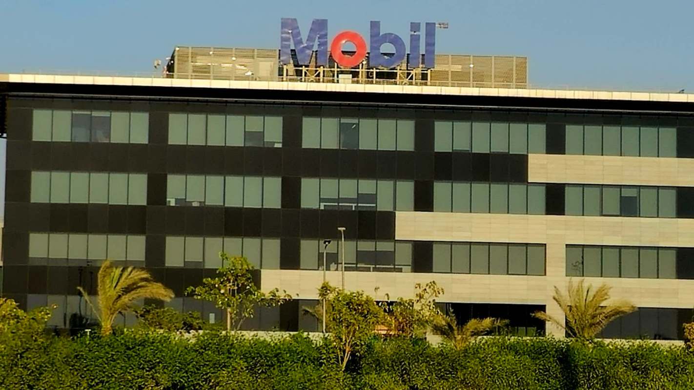 A modern building featuring a prominent blue and red "Mobil" sign on its rooftop.