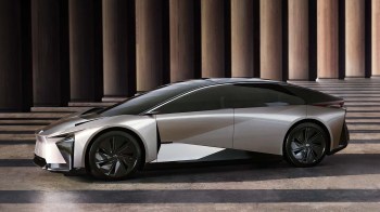 A sleek, futuristic silver electric car is showcased in a modern architectural space.