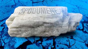 A white mineral displayed against a cracked blue surface.