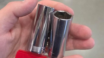 A person holds two shiny metal socket wrenches in their hand.