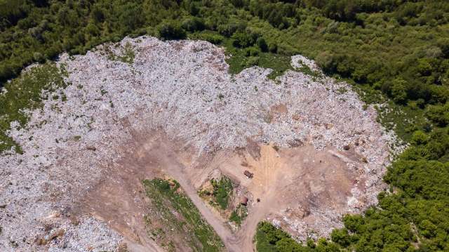 An aerial view of a large landfill surrounded by greenery.
