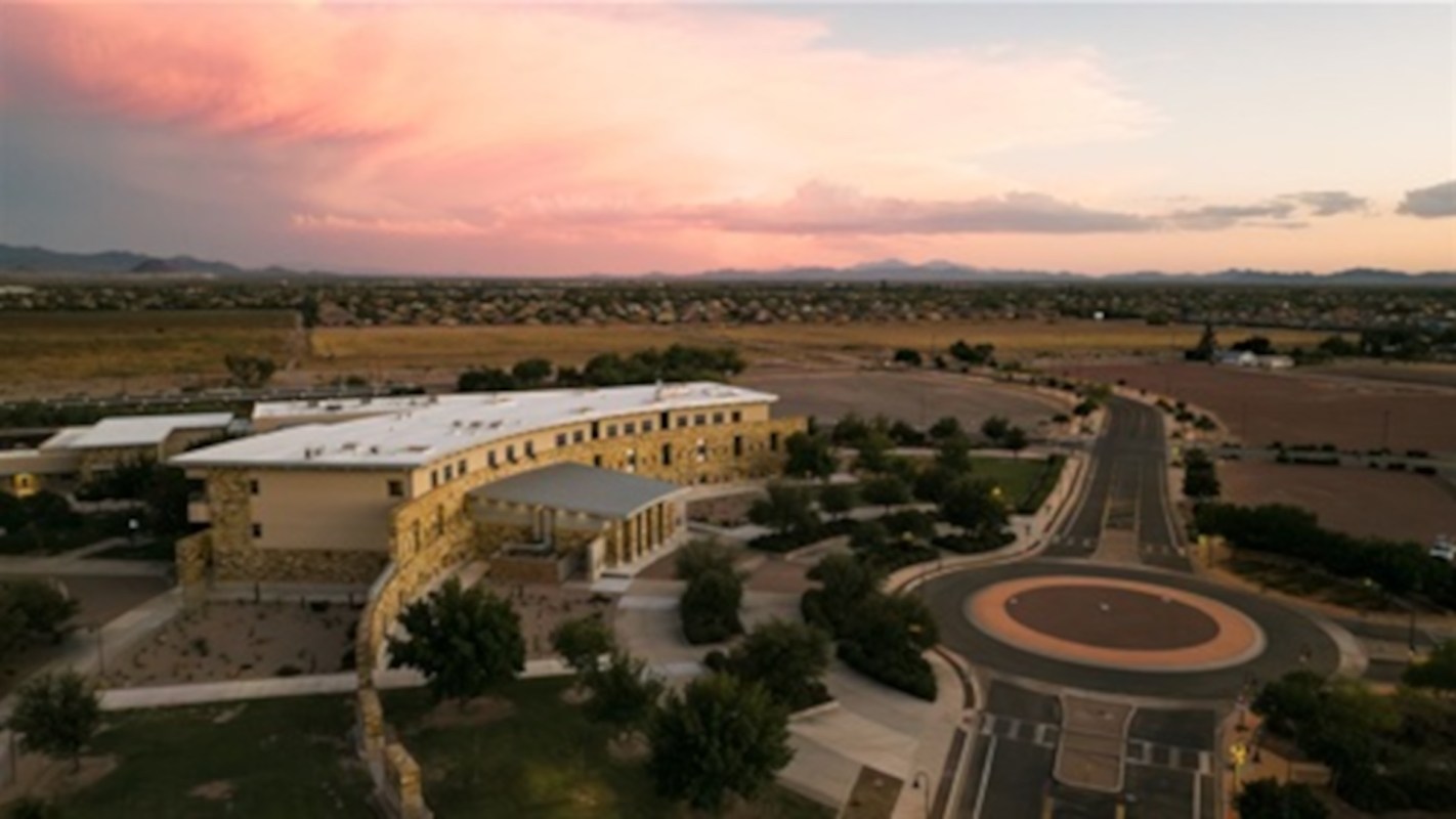 Aerial view of a city at sunset featuring a roundabout in front of a municipal complex.